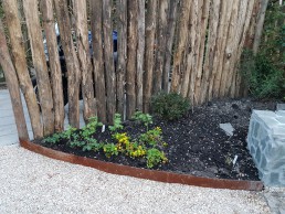 cortenstalen rand langs border en acacia rondpalen afscheiding