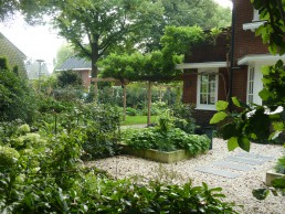 Hoektuin Naarden gemengde borders met gazon en pergola hoogteverschil door betonnen bakken